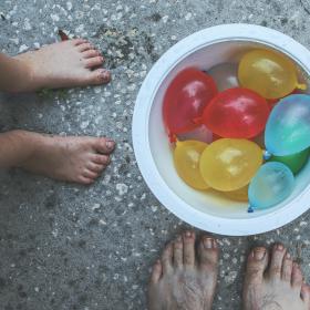 Standing around a bucket of water balloons