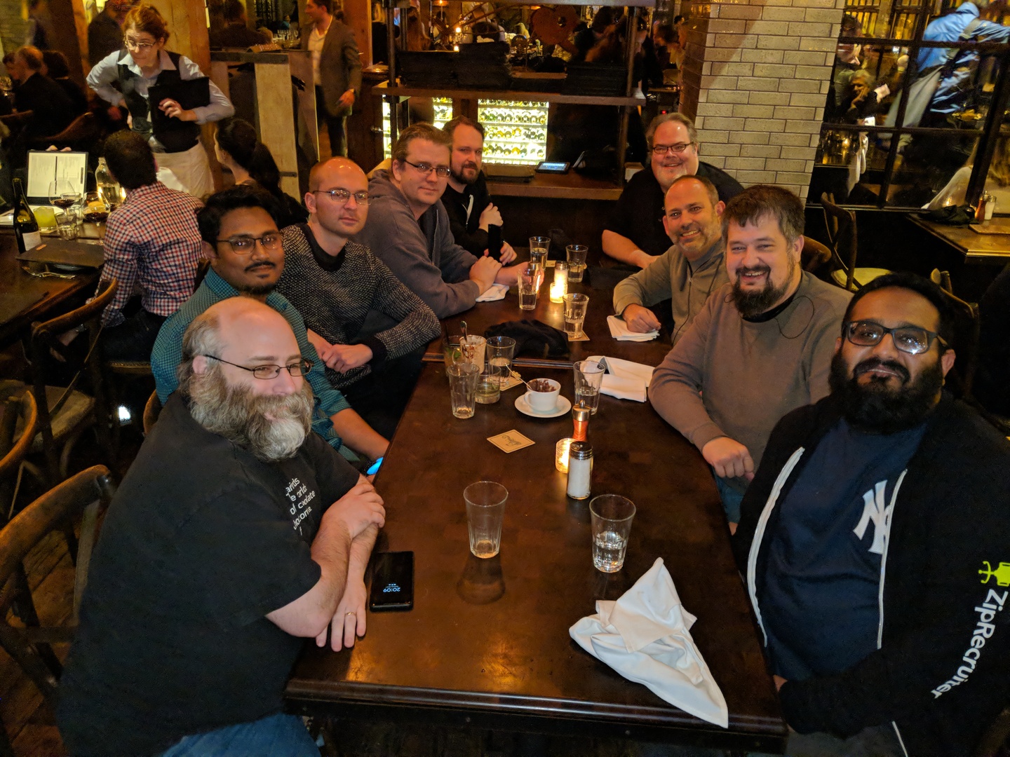 A picture of several people sitting around a table in a busy restaurant with drinks.