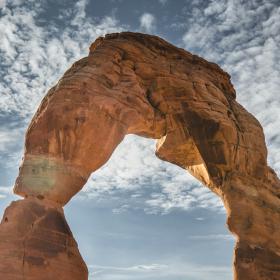A hiker standing under a great stone archway.